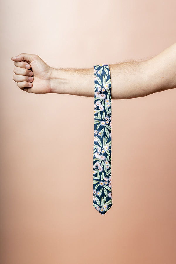 100% cotton tie with flowering gum motif, showcasing vibrant pink blooms against a subtle blue backdrop, designed for sophisticated looks